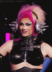 a drag queen wearing headphones with spikes on them and a black top