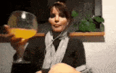a woman is holding a glass of orange juice while wearing headphones .