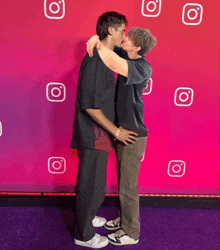 two men are kissing in front of a pink background with instagram icons on it