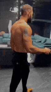 a man with a tattoo on his arm is standing in front of a couch