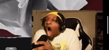 a man wearing headphones and a yellow headband is yawning while playing a video game .