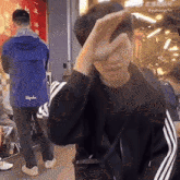a man wearing a rapha jacket covers his face with his hand