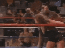 a woman is standing in a boxing ring with a crowd watching .
