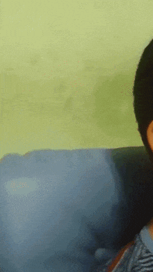 a person sitting on a blue couch with a yellow wall behind them
