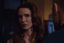 a woman with red hair is looking at a man