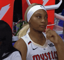 a female basketball player wearing a mystics jersey looks to the side
