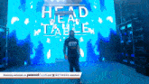 a man standing in front of a large screen that says head table