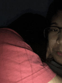 a woman wearing glasses and a red shirt looks down