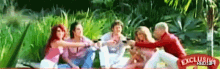 a group of people are sitting on a blanket in a park with a banner that says exclusive rbd gif