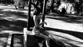 a woman is sitting on a bench in a park under a canopy .
