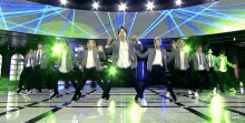 a group of people are dancing on a stage with green lights behind them .