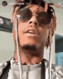 a close up of a person wearing sunglasses and a necklace