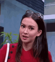 a woman wearing sunglasses and a red sweater is looking at the camera .