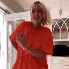 a woman in a red t-shirt is dancing in a room