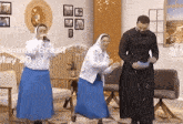 two nuns and a priest are dancing in a room with the date may 20 on the wall