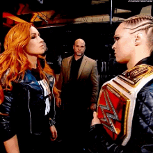 two women are standing next to each other and one is wearing a wrestling championship belt