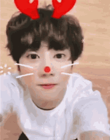 a young boy with a red nose and reindeer antlers on his head .
