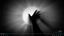 a black and white video with a hand reaching out towards the sun