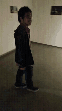 a man is walking in a dark room with a painting on the wall behind him