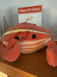 a stuffed crab sits next to a birthday card that says happy birthday