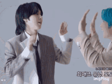 two men in suits and ties are giving each other a high five in front of a sign that says imgplay