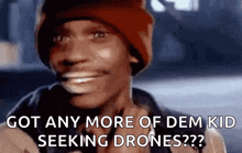 a man wearing a red beanie is smiling and asking if he has any more of dem kid seeking drones .