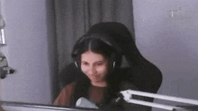 a girl wearing headphones is sitting in a chair in front of a computer screen .