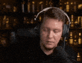 a man wearing headphones looks at the camera with a serious look on his face