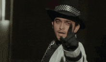 a man wearing a cowboy hat and tie is pointing his finger at the camera .