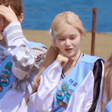 a girl with blonde hair is wearing a blue shirt with korean writing on it and a ponytail .