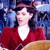 a woman in a red jacket and hat holds a basket of lemons