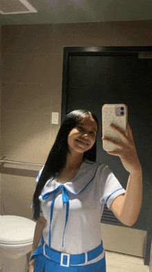 a girl in a school uniform takes a selfie with her phone in a bathroom