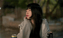 a woman is sitting at a table with a can of soda and a bottle .