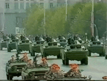 a group of military vehicles are driving down the street