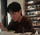 a man is eating a salad with chopsticks in front of a wine rack