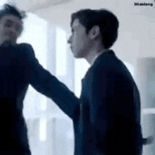 two men are standing next to each other in a room .