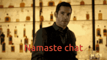 a man stands in front of a shelf full of alcohol bottles with the words namaste chat written in red