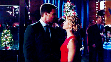 a man in a suit and a woman in a red dress are dancing together in a crowded room .