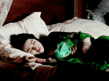 a woman in a green dress sleeps on a bed