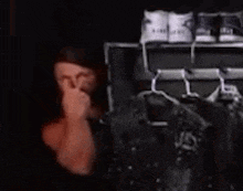 a blurry picture of a person covering their nose in front of a closet filled with clothes .