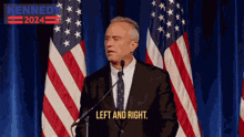 a man in a suit and tie is giving a speech in front of an american flag with a sign that says kennedy 2024