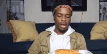 a man is sitting on a couch eating a pizza