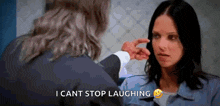 a woman in a prison uniform is laughing while a man holds her hand to her face .