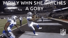 a football player is catching a pass on a field while another player watches .