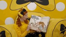 a woman in a yellow outfit is reading a book to a child