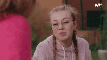 a girl wearing glasses is making a funny face while sitting at a table .