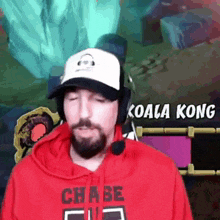 a man with a beard wearing a hat and headphones and a red hoodie with the word chase on it