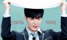 a young man in a suit and tie is holding a tray on his head
