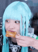 a girl with blue hair is eating a piece of chicken