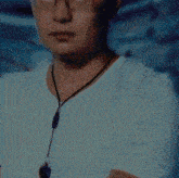 a man wearing glasses and a lanyard around his neck looks at the camera